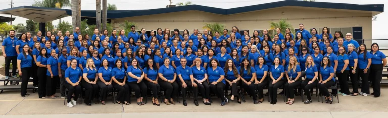 Parent volunteers and AESD staff posing for a group photo in tiered rows, wearing matching blue AESD parent engagement shirts.